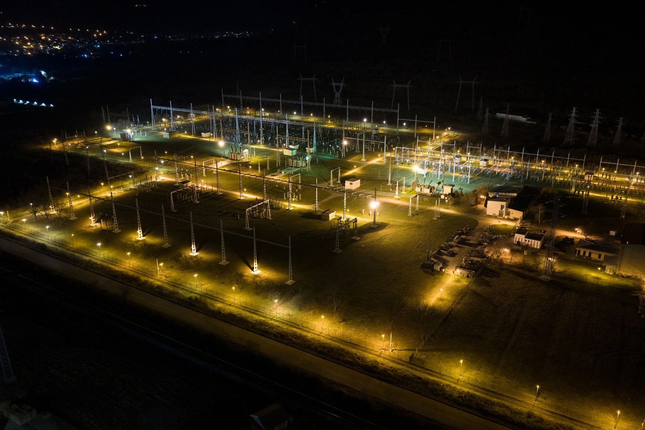 Aerial night view of illuminated electrical infrastructure representing large-scale energy projects